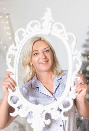 Young beautiful woman holding a frame in front of her face.の写真素材