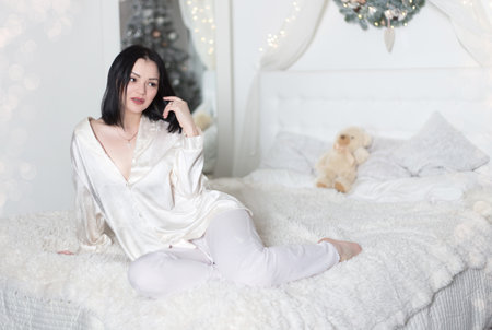 Young beautiful woman in pajamas in the bedroom. Winter holiday.の写真素材