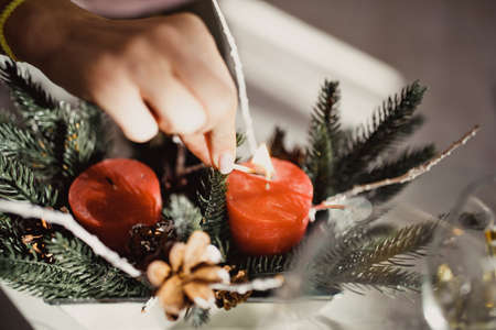 Woman lights a candle for Christmas or New Year, festive decor close-up. High quality photoの写真素材