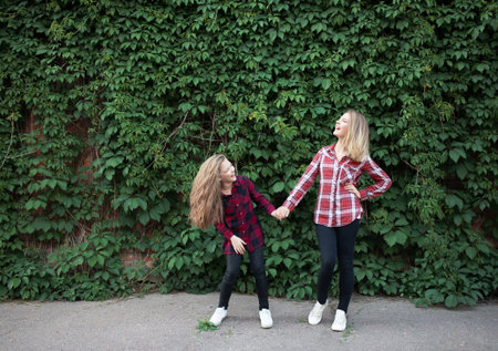 Young mother and daughter are having fun on a walk on a sunny warm day. Joyful emotions.