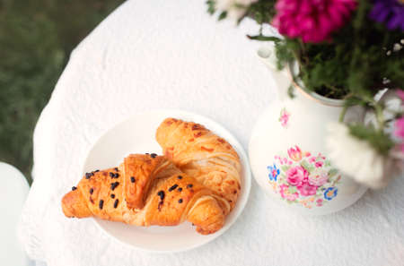 Croissants on a plate in a summer garden or on a terrace in a cafe close-up.の写真素材