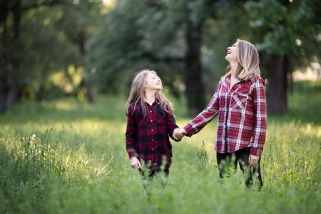 Young mother and daughter are having fun on a walk on a sunny warm day.の写真素材