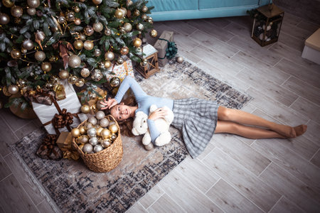 Cute teenage girl in a room with a decorated Christmas tree. The winter holidays.の写真素材
