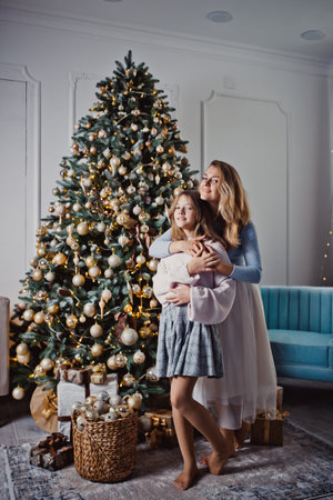 Mother and daughter at home near the Christmas tree. Winter holidays.の写真素材