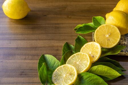 Close up of lemon and green leaves on wooden backgroundの写真素材