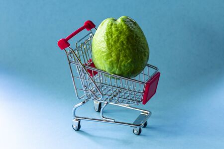 red guava plants inside supermarket cart on blue background.の写真素材