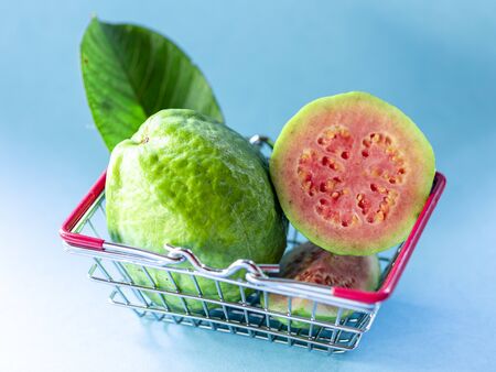 Several slices of red guava fruit in supermarket basket on blue background.の写真素材