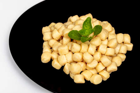 Pile of fresh raw gnocchi with basil leaves, view from above on a black dishの写真素材