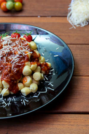 Close up on traditional italian potato gnocchi in tomato sauce with fresh basil and Cherry tomatoの写真素材