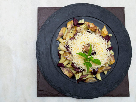 Pasta with black olives, Parmesan cheese, artichoke hearts, topped with fresh basil leaves.