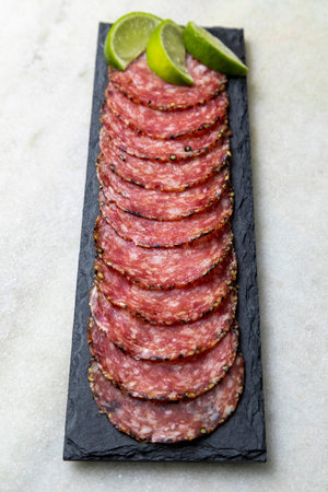 Portion of salami on black stone plateの写真素材