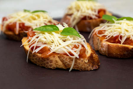 Bruschetta with tomato, basil and mozzarella cheese on wooden board. Traditional Italian appetizer or snack, antipastoの写真素材