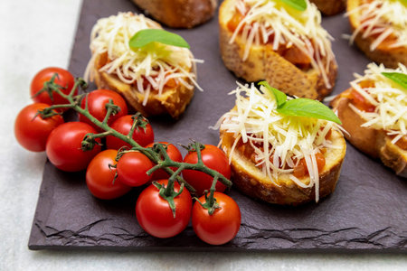 Bruschetta with tomato, basil and parmesan cheese on wooden board. Traditional Italian appetizer or snack, antipastoの写真素材