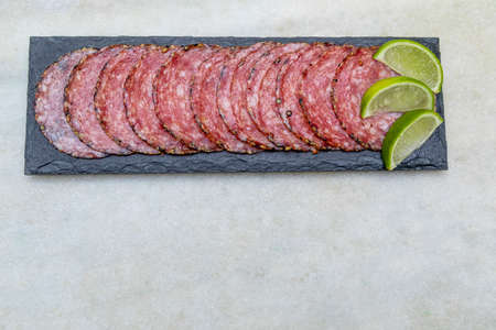 Portion of salami on black stone plateの写真素材