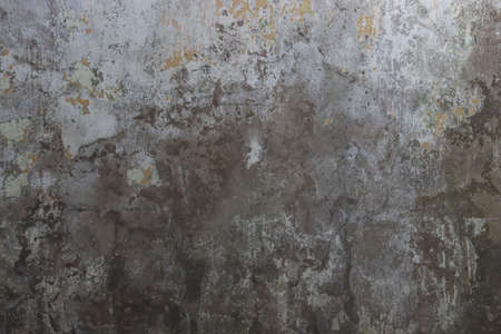 The texture of a worn out, old concrete wall with peeling paint.