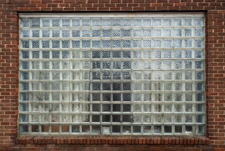 Wide window made of patterned square glass tiles in red brick wallの写真素材