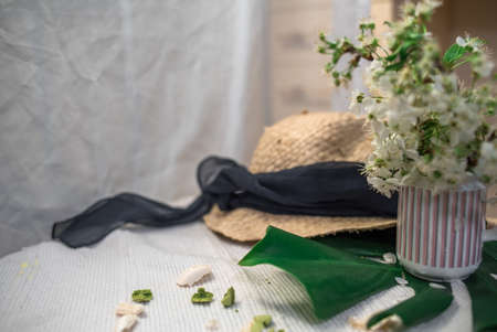 Crushed pastel, orange and green macaroons on a wood background with whole one in white plate with jug with flowers on the backの写真素材