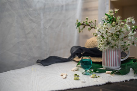 Crushed pastel, orange and green macaroons on a wood background with whole one in white plate with jug with flowers on the backの写真素材