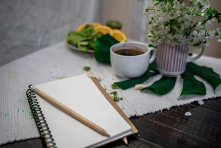 Crushed pastel, orange and green macaroons on a wood background with whole one in white plate with jug with flowers on the backの写真素材