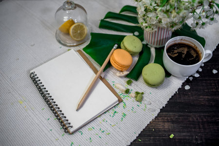 Crushed pastel, orange and green macaroons on a wood background with whole one in white plate with...