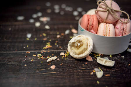 Rose and beige macaroons on a wooden tableの写真素材