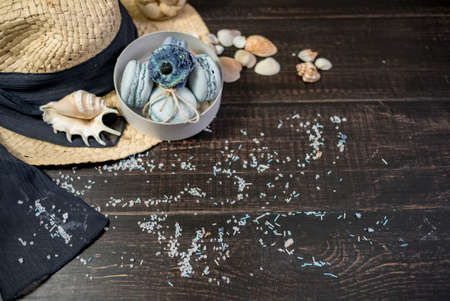Straw hat with blue macaroons and sea salt with shells on the wood backgroundの写真素材