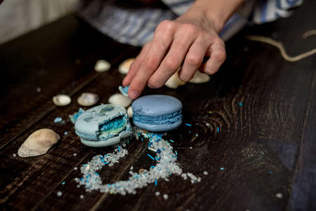 Straw hat with blue macaroons and sea salt with shells on the wood backgroundの写真素材