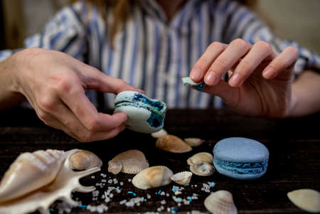 Straw hat with blue macaroons and sea salt with shells on the wood backgroundの写真素材