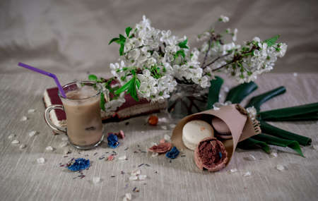 A book for notes with a pencil with hot cocoa in flower petals and crusshed macaroons on pastel backgroundの写真素材