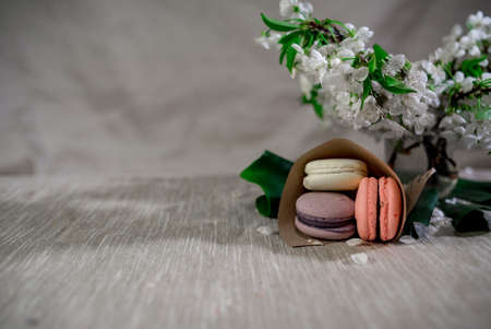 Multicolor macaroons on a table with eastern vase and cherry branch in blossomの写真素材