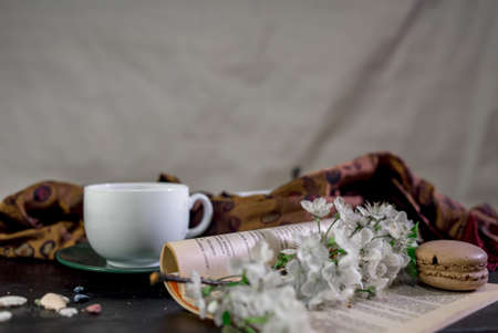 A cup of coffee on a white tray with branch of blossomed cherry and monstera leafの写真素材