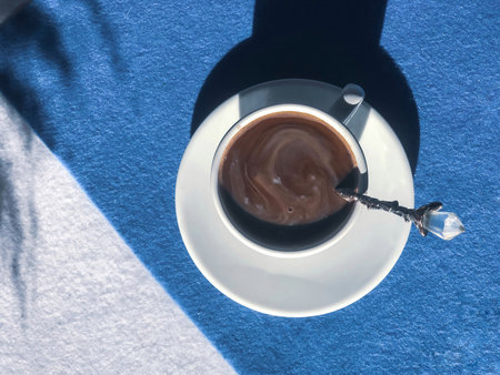 Coffee in a white cup with a spoon with ice-cream on a blue and white background