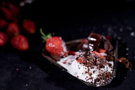 White ice cream with chocolate drops with strawberries on a black backgroundの写真素材