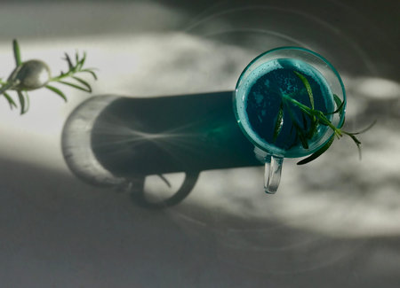 Blue cold drink in a glass with ice cubes on white desk with blue background. Also used mint leaves...