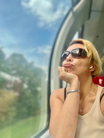 Portrait of a beautiful woman in sunglasses on the background of the windowの写真素材