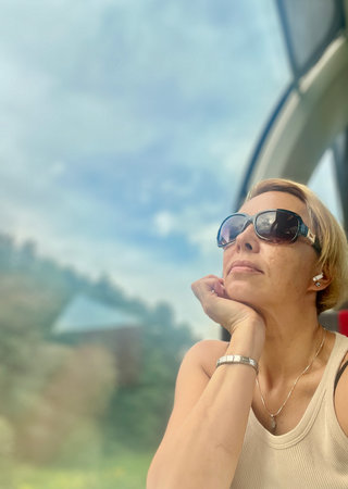 Portrait of a beautiful mature woman in sunglasses on the background of the windowの写真素材