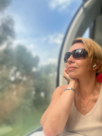 Beautiful young woman with short blond hair and sunglasses on the trainの写真素材