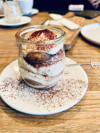 Tiramisu in a glass cup on a wooden table.の写真素材