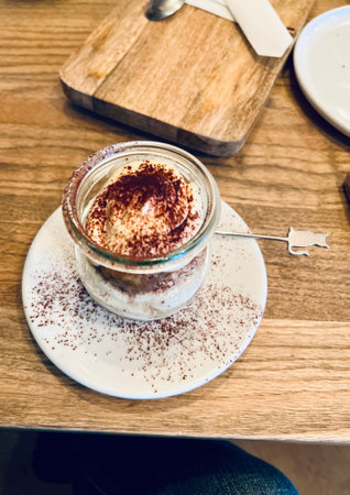 Tiramisu in a glass cup on a wooden table.の写真素材