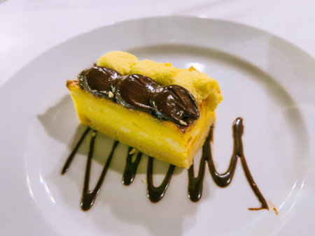 A piece of cake on a white plate with chocolate and coffee beansの写真素材