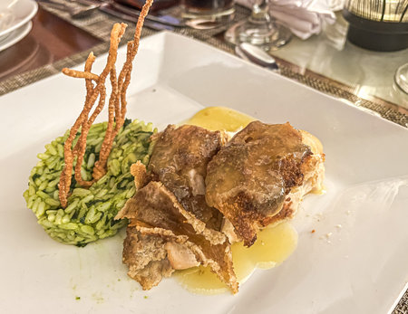 Crispy fried pork with rice on a white plate in a restaurant