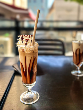 Iced coffee with whipped cream and chocolate syrup in a glass.
