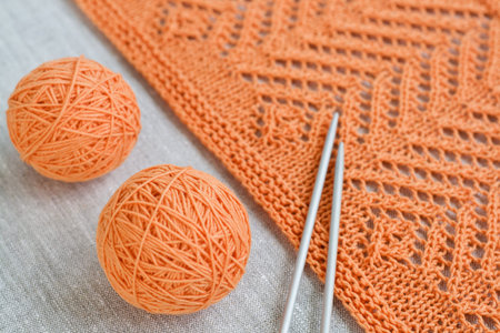 Orange balls, knitted pattern and knitting needles
