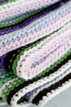Knitting striped rug with white, purple, green and pink stripes