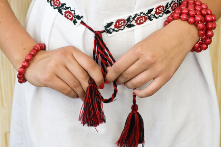 Girls hands with red bracelets and traditional embroidered shirtの写真素材