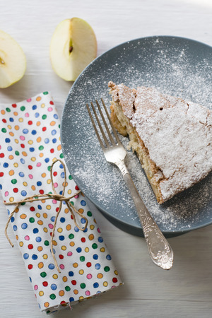 A piece of apple pie lying on the gray plate, apple, fork on a colored backgroundの写真素材
