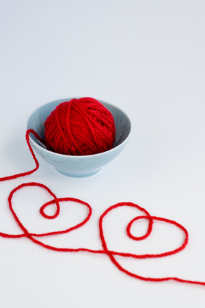 Two red hearts made from yarn, yarn ball of red and blue plateの写真素材