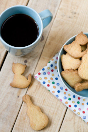Sweet tasty cookies in the blue plate and cup of black coffee on the wooden unpainted background.の写真素材
