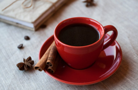 Red cup of coffee with coffee beans and spices cinnamon and anise starの写真素材