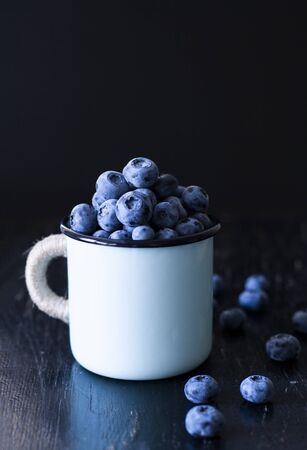 A tasty and healthy snack: a mug of juicy and sweet blueberries on the black background.の写真素材